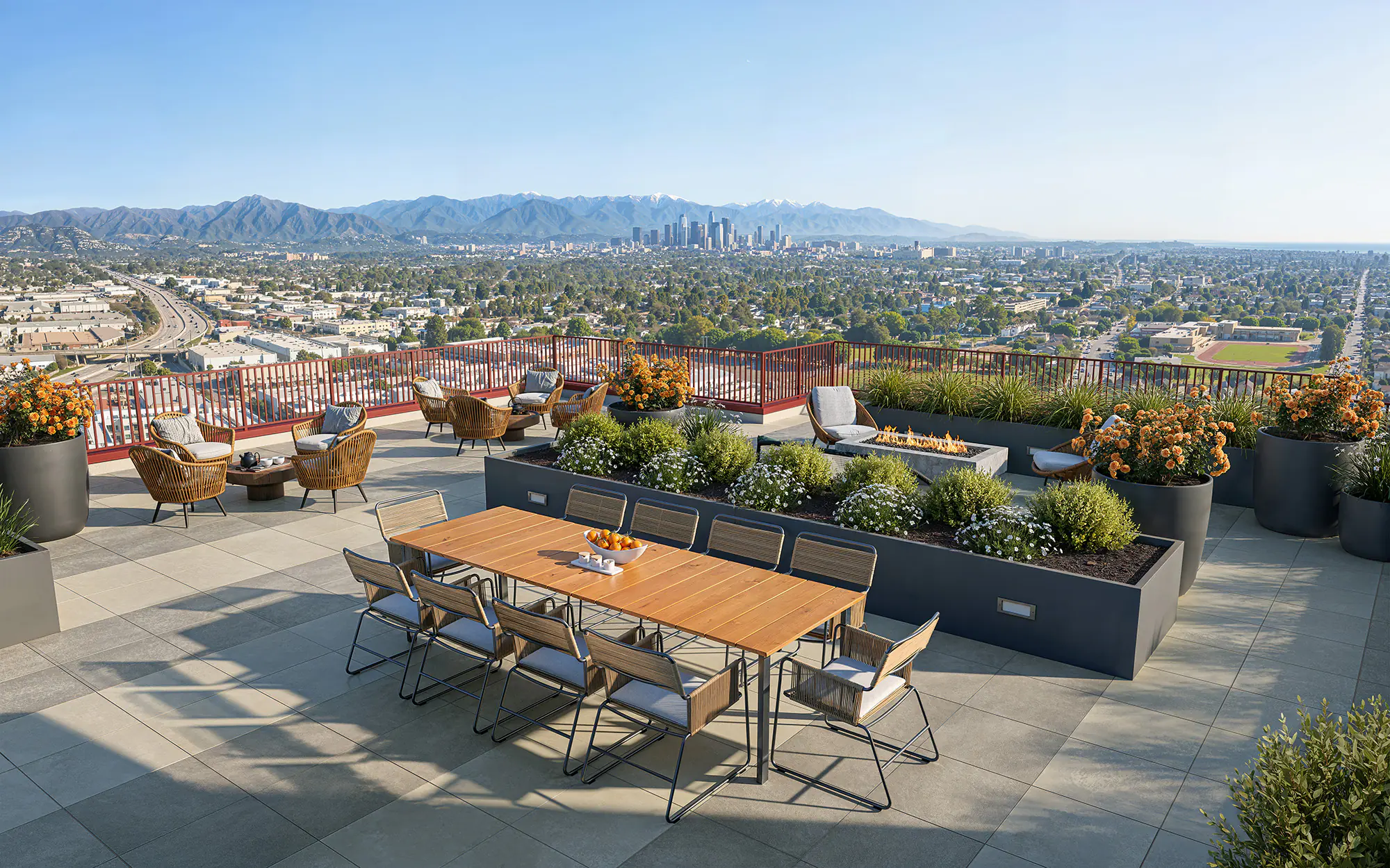 Rooftop deck with communal dining, fire feature, and skyline views toward downtown Los Angeles — The Clark on 54th